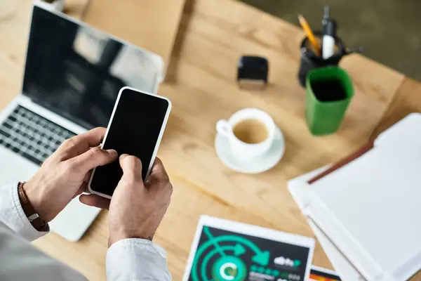 A redhead professional in a white shirt is engaged with a smartphone while planning projects at his desk. — Stock Photo