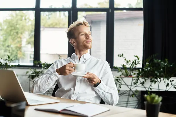 A focused redhead businessman in a white shirt reflects while savoring coffee in a stylish office setting. — Stock Photo