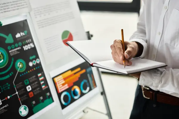 Professional in a white shirt writes notes on a project in a contemporary office space. — Stock Photo
