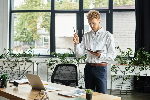 A focused businessman with red hair stands with a notebook, passionately brainstorming ideas at his desk. — Stock Photo
