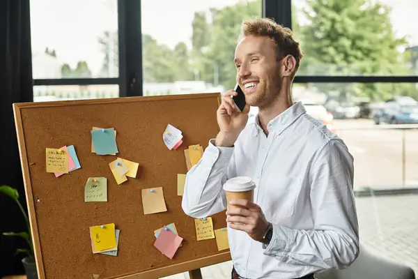 A redheaded businessman in a white shirt collaborates on a project while enjoying coffee in modern surroundings. — Stock Photo