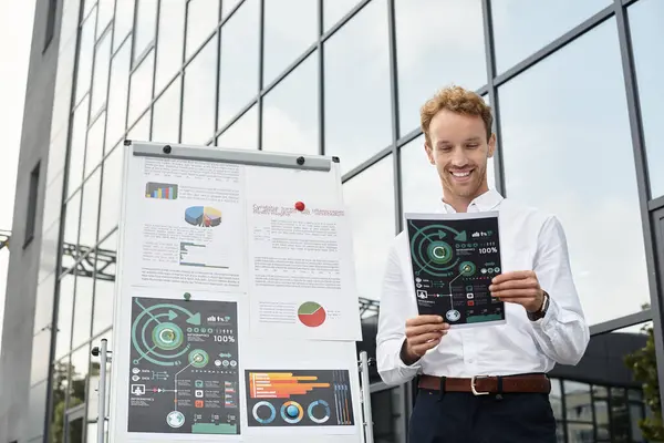 In a contemporary office, a redhead businessman engages in a project, reviewing materials and smiling. — Stock Photo