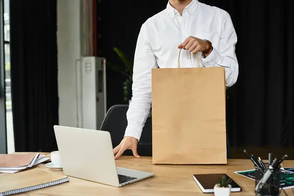 A redheaded businessman in a white shirt stands in a stylish office, engaged in his work with a shopping bag. — Stock Photo