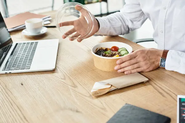 Um empresário dedicado em uma camisa branca faz uma pausa para o almoço, saboreando uma refeição saudável enquanto trabalha. — Fotografia de Stock