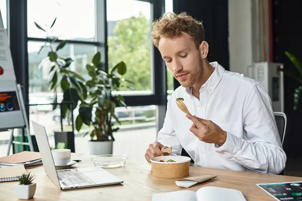 A redhead professional in a white shirt thoughtfully enjoys his lunch, balancing work and nourishment. — Stock Photo