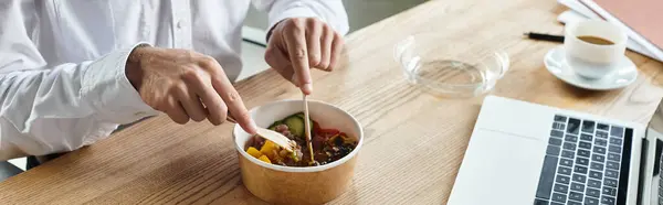Ein Geschäftsmann im weißen Hemd genießt ein nahrhaftes Mittagessen, während er sich auf seine Projektarbeit konzentriert. — Stockfoto