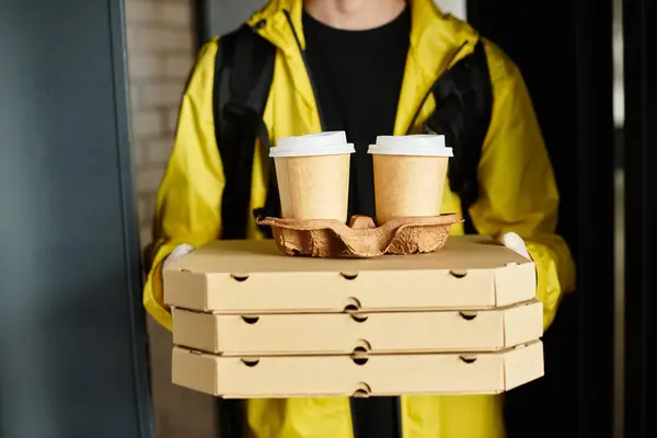 Ein Zusteller in gelber Jacke bringt Pizza und Kaffee ins Büro und sorgt für einen pünktlichen Mittagstisch. — Stockfoto