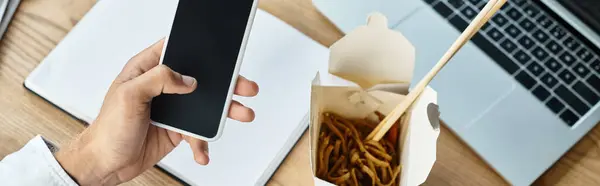 A dedicated professional reviews his project with takeout nearby, balancing work and a quick meal. — Stock Photo