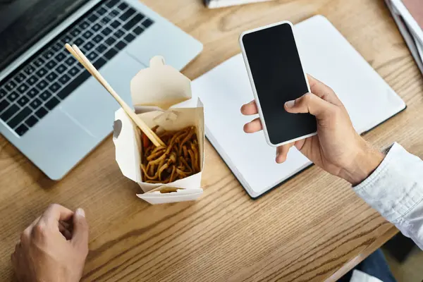 A diligent man in a white shirt reviews a project, taking a brief break with lunch by his side. — Stock Photo