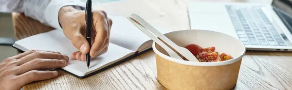 In a contemporary office, a businessman writes notes while enjoying a healthy lunch in a bowl. — Stock Photo