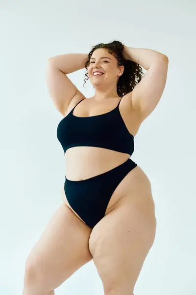 Una donna fiduciosa plus size mette in mostra la sua personalità vibrante in costumi da bagno alla moda, irradiando gioia. — Foto stock