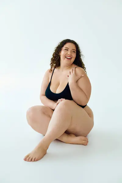Веселая женщина plus size излучает счастье, сидя на полу. — стоковое фото