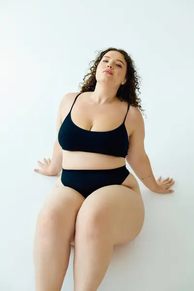 Una donna fiduciosa plus size mette in mostra la sua bellezza mentre seduto con grazia, abbracciando la positività del corpo. — Foto stock