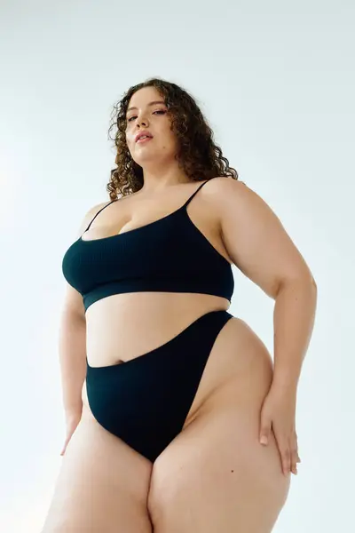Красивая женщина plus size излучает уверенность в черном наряде из двух частей, демонстрируя свои изгибы. — стоковое фото