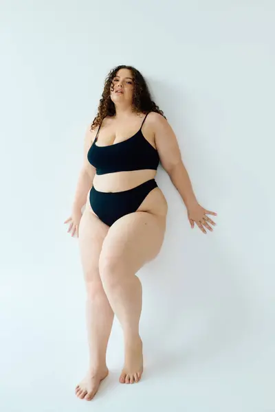 Una mujer confiada y de tamaño grande posa con gracia, mostrando vibrante expresión de sí mismo y belleza. - foto de stock