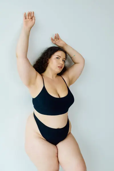 Уверенная в себе женщина plus size сияет в стильном черном купальнике, излучая позитив. — стоковое фото