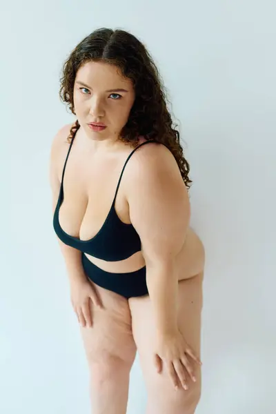 A beautiful plus size woman showcases her confidence and beauty in a chic black bikini. — Stock Photo