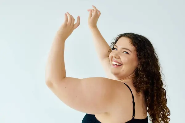 A joyful plus size woman embraces her beauty, radiating confidence in a bright studio. — Stock Photo