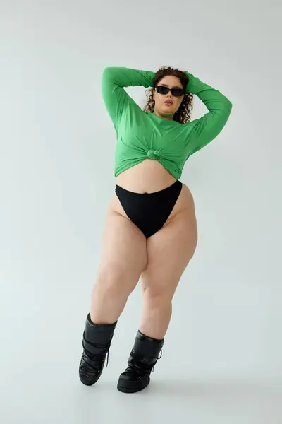 Uma mulher confiante plus size exibe uma roupa verde vibrante em uma pose ousada. — Fotografia de Stock