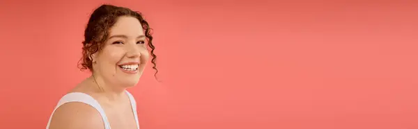 A radiant plus size woman smiles brightly, showcasing her confidence and beauty in a coral setting. — Stock Photo