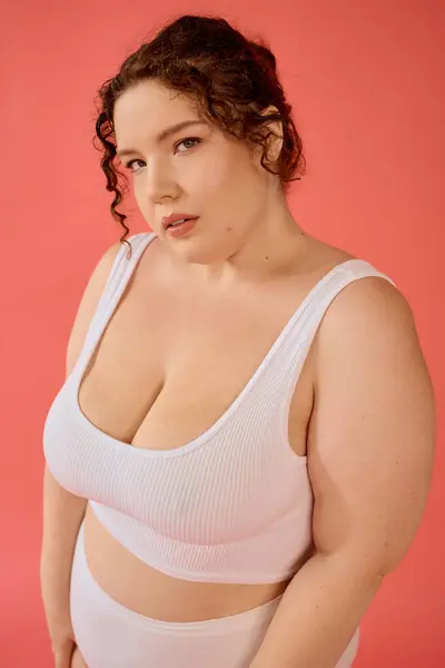 Уверенная в себе женщина plus size демонстрирует свой смелый стиль и радость перед ярким розовым фоном. — стоковое фото