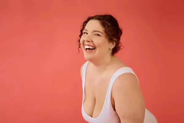 A cheerful plus size woman in a white outfit smiles brightly, showcasing her confidence. — Stock Photo