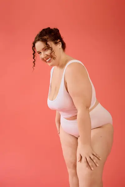 A beautiful plus size woman stands with joy, radiating confidence in a stylish pink outfit. — Stock Photo