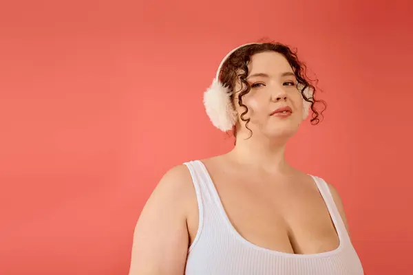 Uma mulher confiante plus size posa graciosamente, adornada em uma roupa aconchegante e amortecedores de ouvido quentes. — Fotografia de Stock