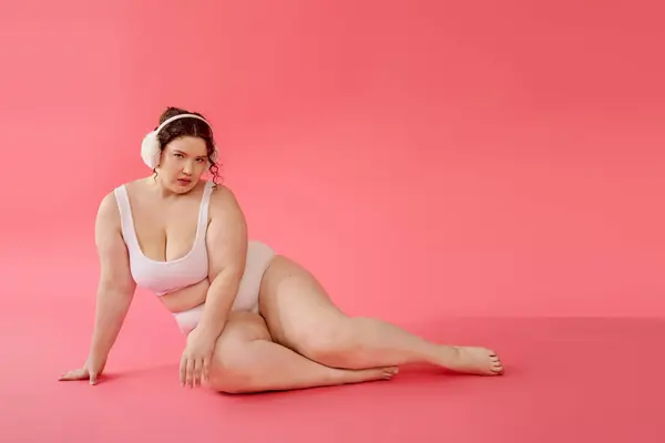 The beautiful plus size woman showcases her elegance while lounging against a bright pink backdrop. — Stock Photo