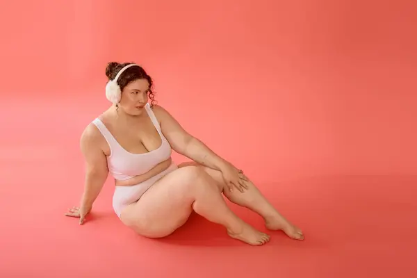 A confident plus size woman poses gracefully against a cheerful coral background. — Stock Photo