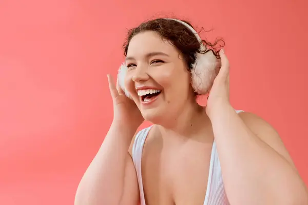 A cheerful plus size woman smiles broadly while embracing her love for music on a bright background. — Stock Photo