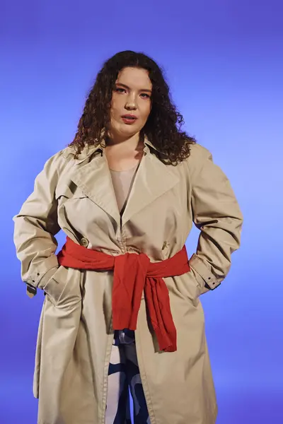 A beautiful plus size woman showcases her confidence in a fashionable trench coat with a chic belt. — Stock Photo