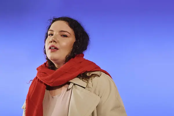 A confident plus size woman highlights her beauty with a bold red scarf on a bright backdrop. — Stock Photo