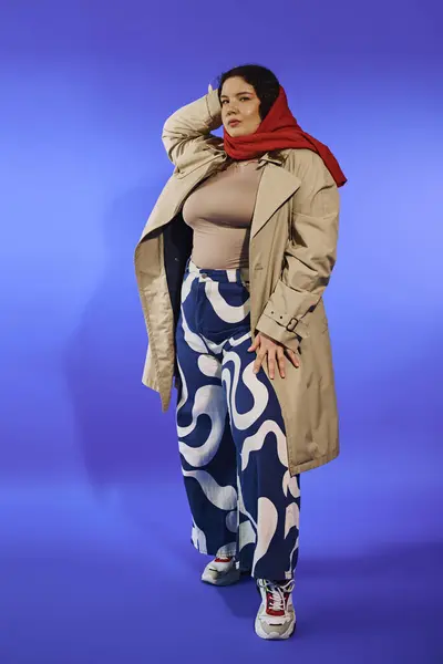 A plus size woman exudes elegance in stylish attire with a striking red scarf and pattern pants. — стоковое фото