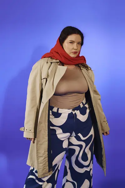 A stunning plus size woman strikes a pose in unique patterned pants and a stylish trench coat. — Stock Photo