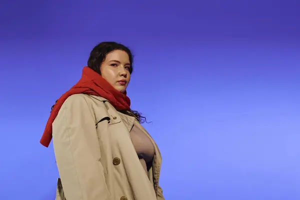 She stands tall and poised, showcasing confidence in a stylish coat with a bold red scarf. — Stock Photo