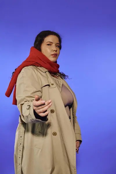 A confident plus size woman stylishly poses in a trench coat and scarf. — Stock Photo