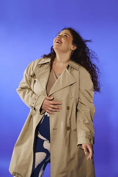 Una donna plus size irradia fiducia mentre ride giocosamente, vestito con un trench chic. — Foto stock