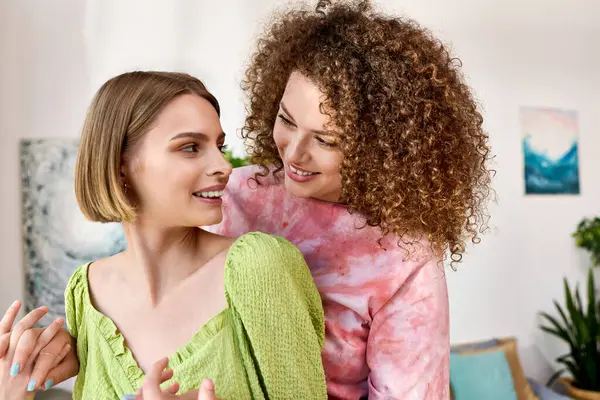 Two young women embrace warmly, sharing laughter and love in a colorful room. — Stock Photo