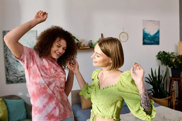 Duas jovens dançam brincando juntas em seu confortável espaço de vida, compartilhando alegria. — Fotografia de Stock