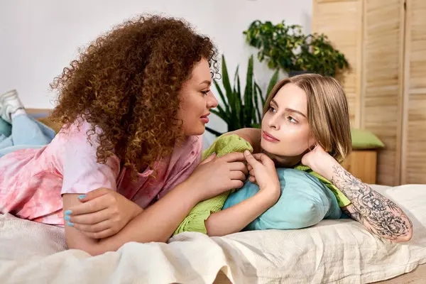Two young women enjoy a tender moment together while lounging comfortably in a bright living space. — Stock Photo