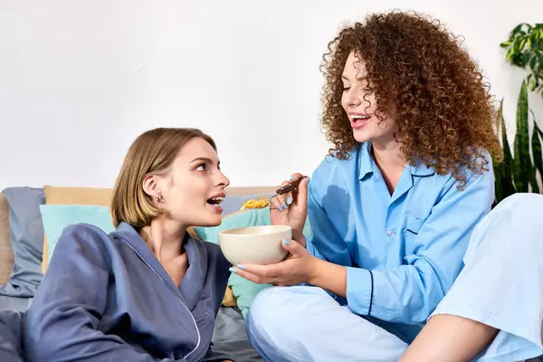 A happy couple shares smiles and food while relaxing in their cozy living room. — Stock Photo