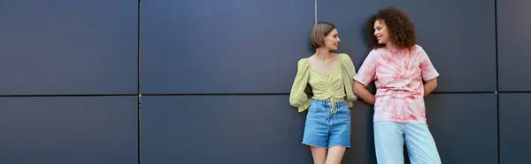 Two young women enjoy a cheerful moment together, exchanging smiles in a stylish urban setting. — Stock Photo