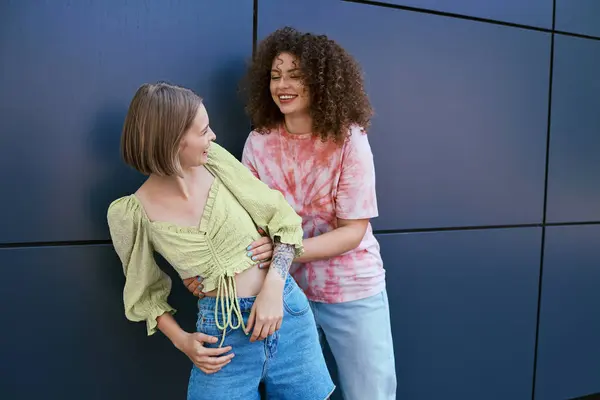 Two women share a light hearted embrace, laughing joyfully in a modern environment. — Stock Photo