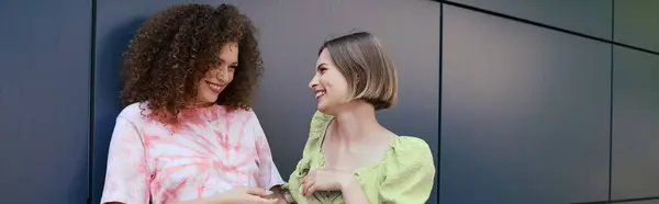 A cheerful young lesbian couple enjoys each others company, smiling and chatting casually. — Stock Photo