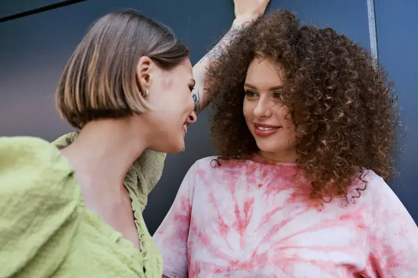 Two young women share a warm laughter while connecting in a lively urban environment. — Stock Photo