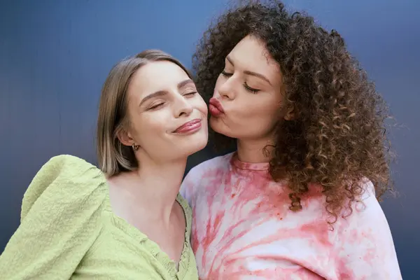 Two young women share a loving embrace, radiating joy and affection in a colorful setting. — Stock Photo