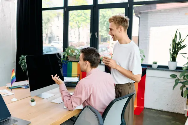 A charming gay couple shares laughter and ideas while working together in a lively office. — Stock Photo