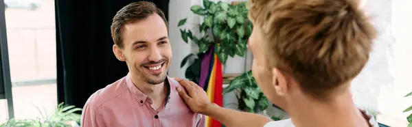 Two men share a warm smile, enjoying a playful interaction in a bright, plant filled space. — Stock Photo