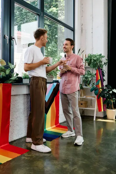 A joyful pair share laughter and drinks while surrounded by vibrant decorations and greenery. — Stock Photo